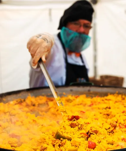 Gary from your paella stirring a large pan of paella