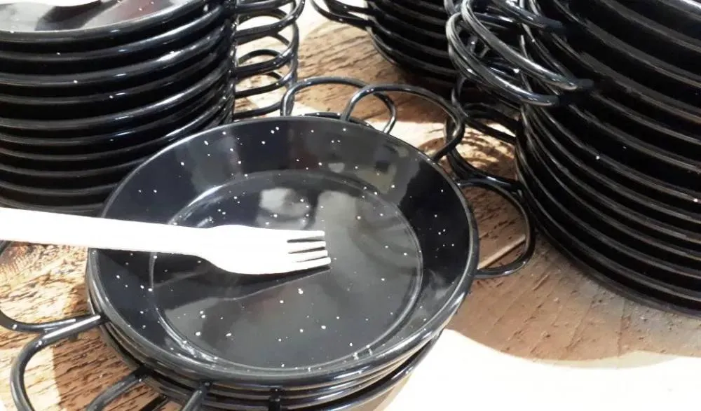 Premium black individual paella serving pans with wooden forks from our Paella Catering Menu
