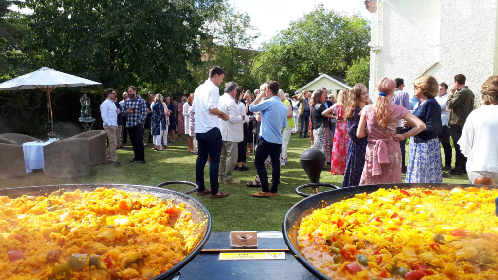 Wedding guests enjoying freshly cooked paella from the Your Paella Cart at a private outdoor wedding reception in the UK.