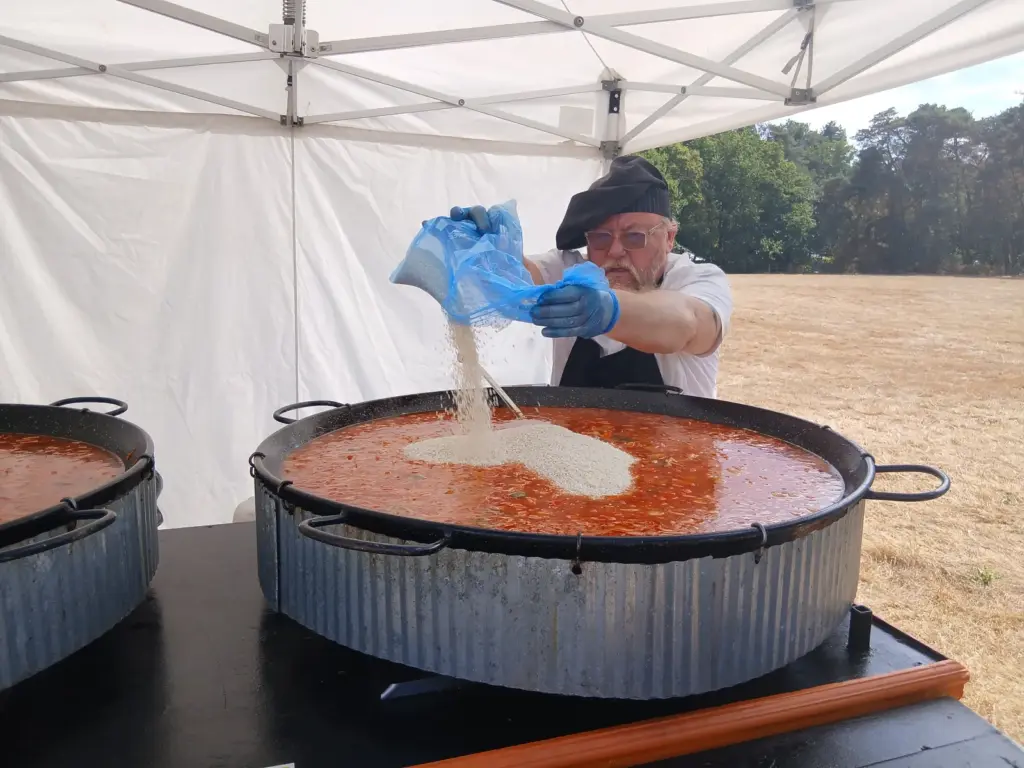 Adding rice while cooking paella for 120 wedding guests